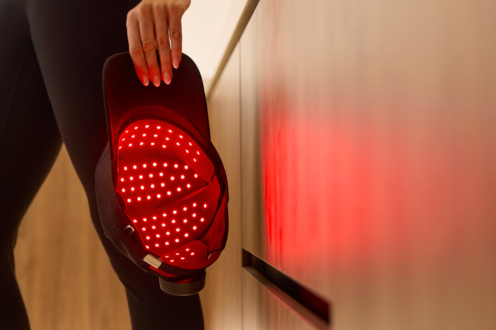 Person holding a red light cap, glowing red, reflected on nearby surface 